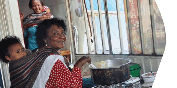 Woman with child on her back using stove