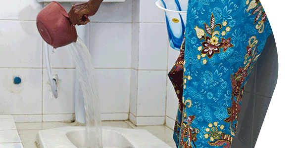 woman in colorful dress disposing waste water into toliet